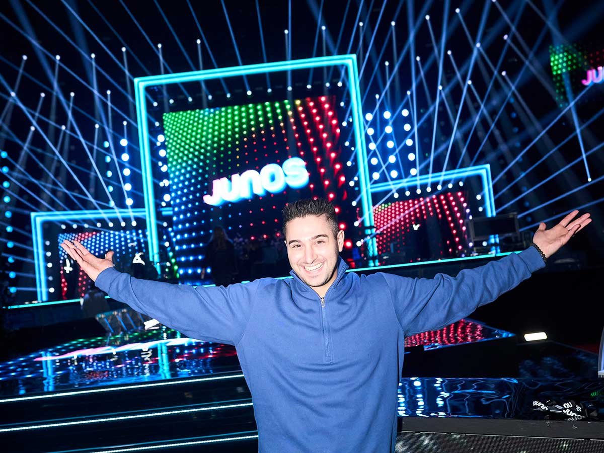 Man stands with his arms outstretched in front of a stage at The Juno Awards 