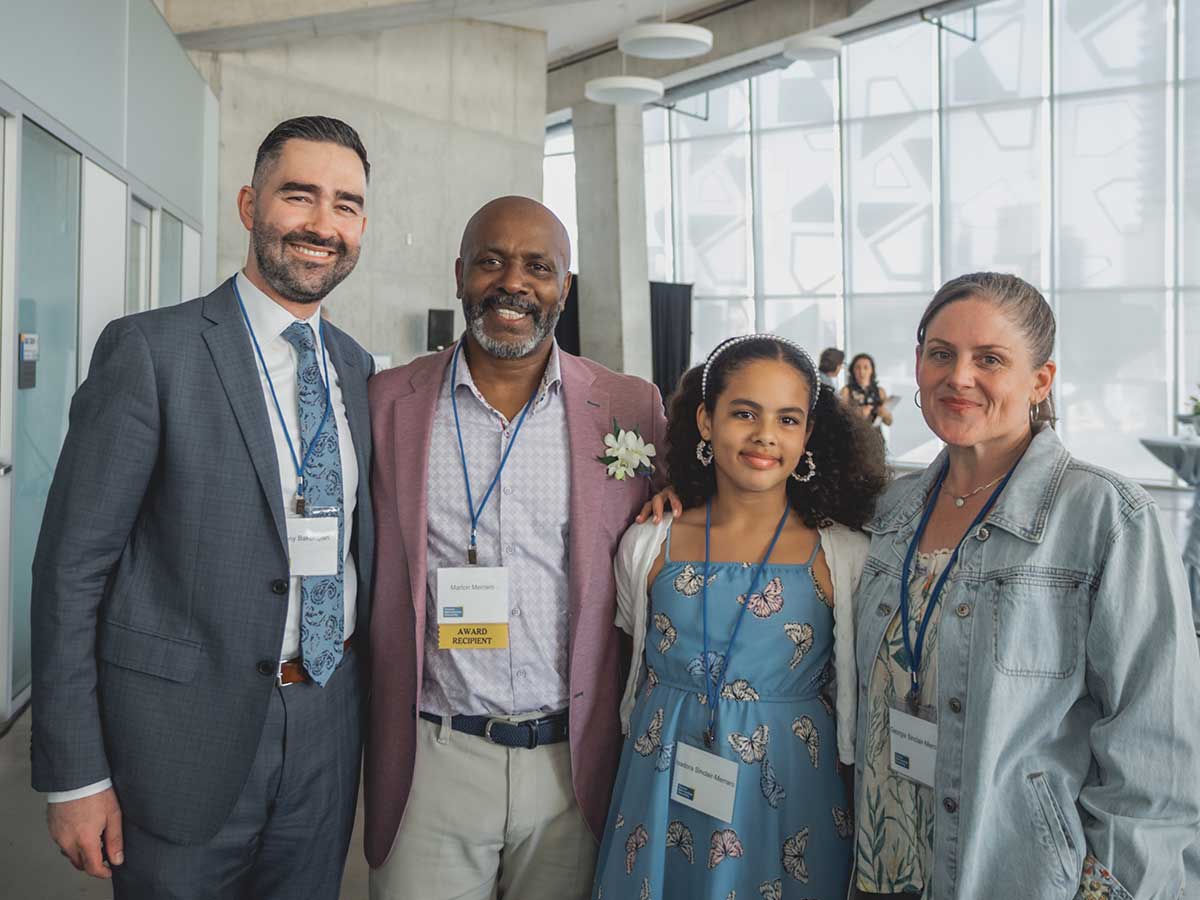 A TMU staff member poses alongside a recipient and his family
