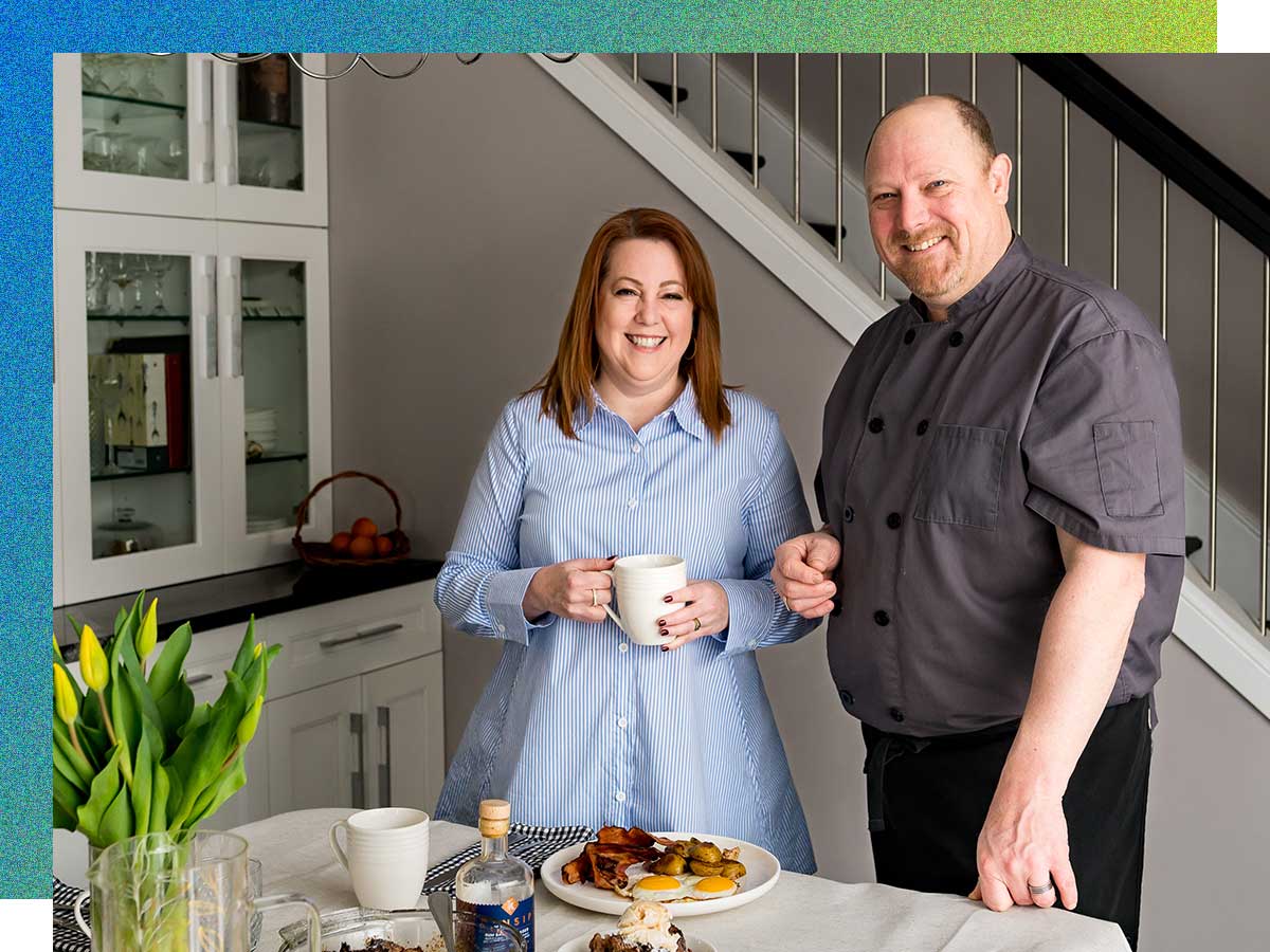 A man and woman stand in the dining area of their bed and breakfast. Credit – Christine Reid, Christine Reid Photography 