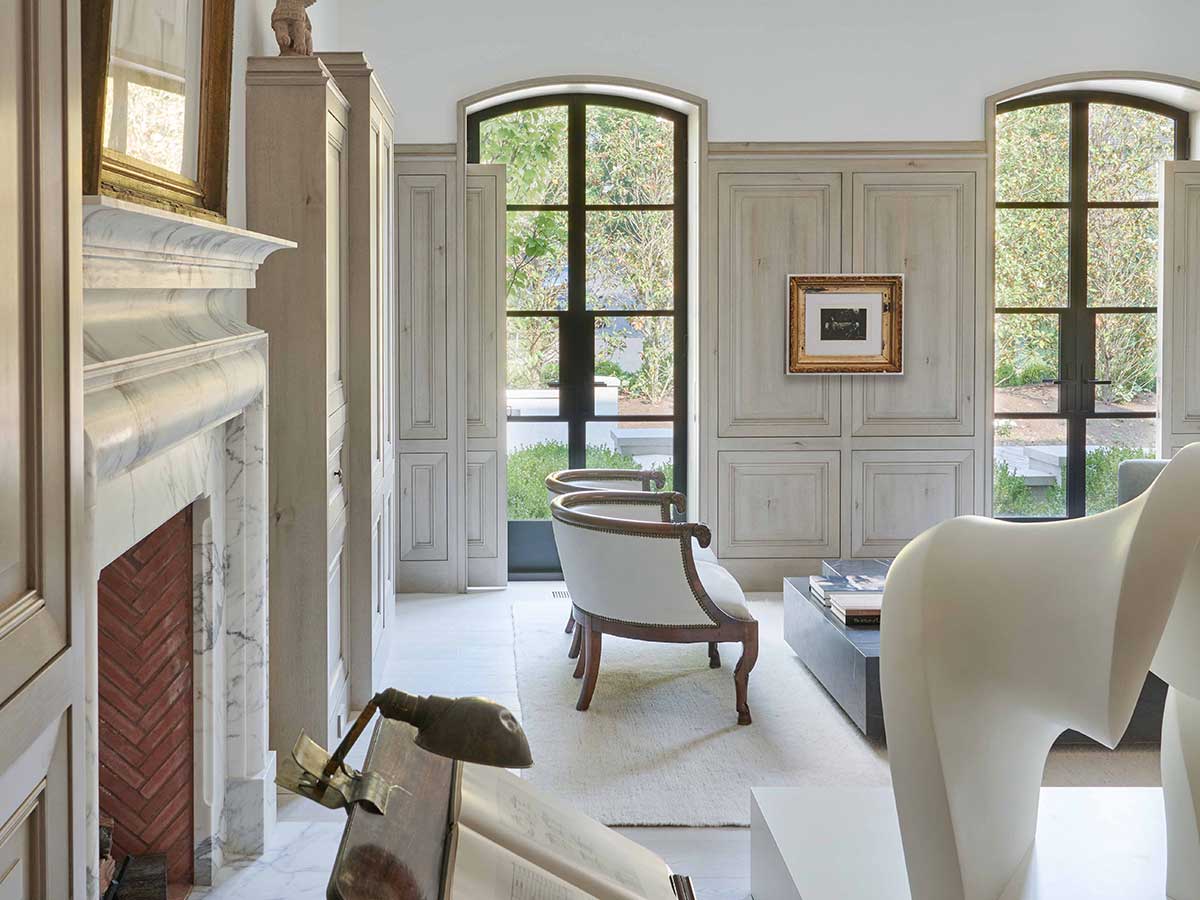 A living room with a fireplace and chairs inside a traditional style home.