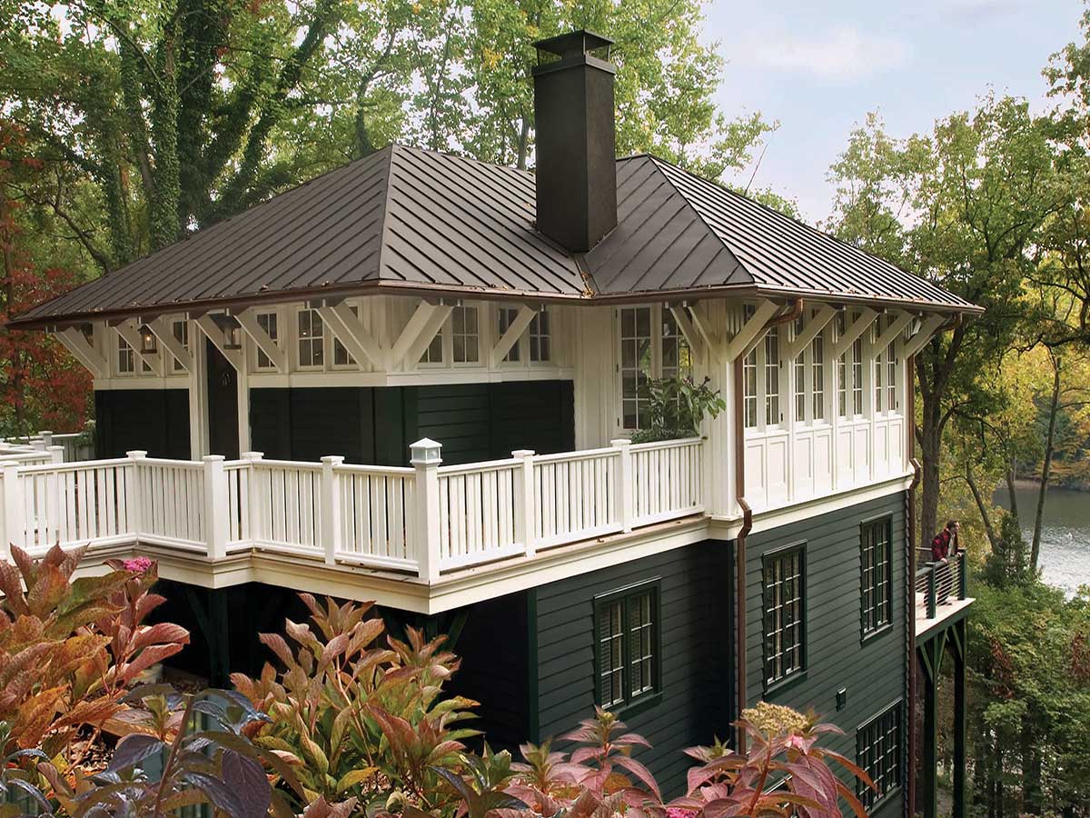 The exterior of a home, painted green with white trim on a terrace and a brown roof.