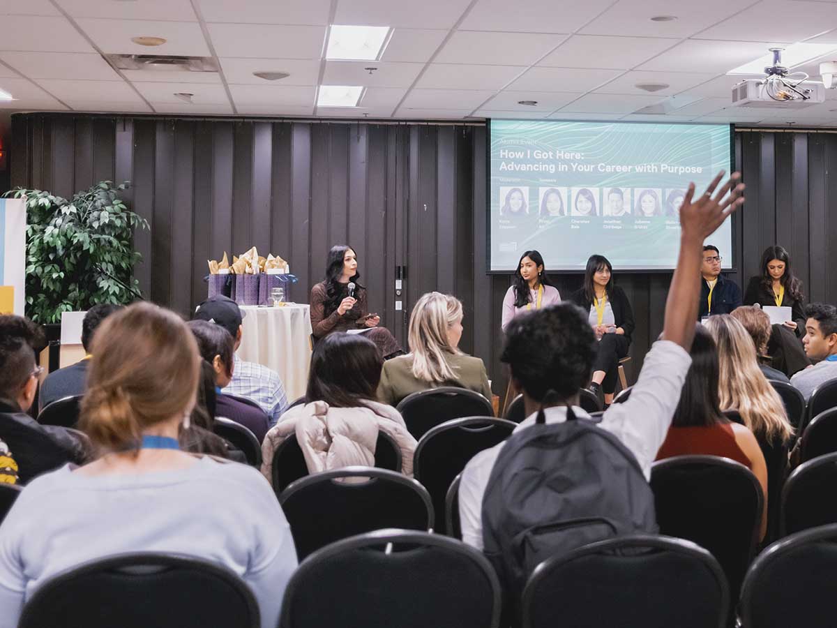 An audience member raises his hand to ask the panellists a question.