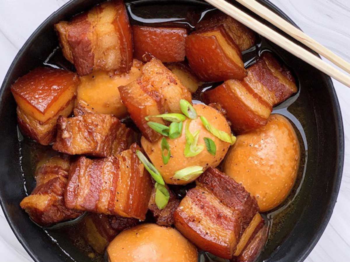 A black bowl contains food, chopsticks balanced on the edge of the bowl