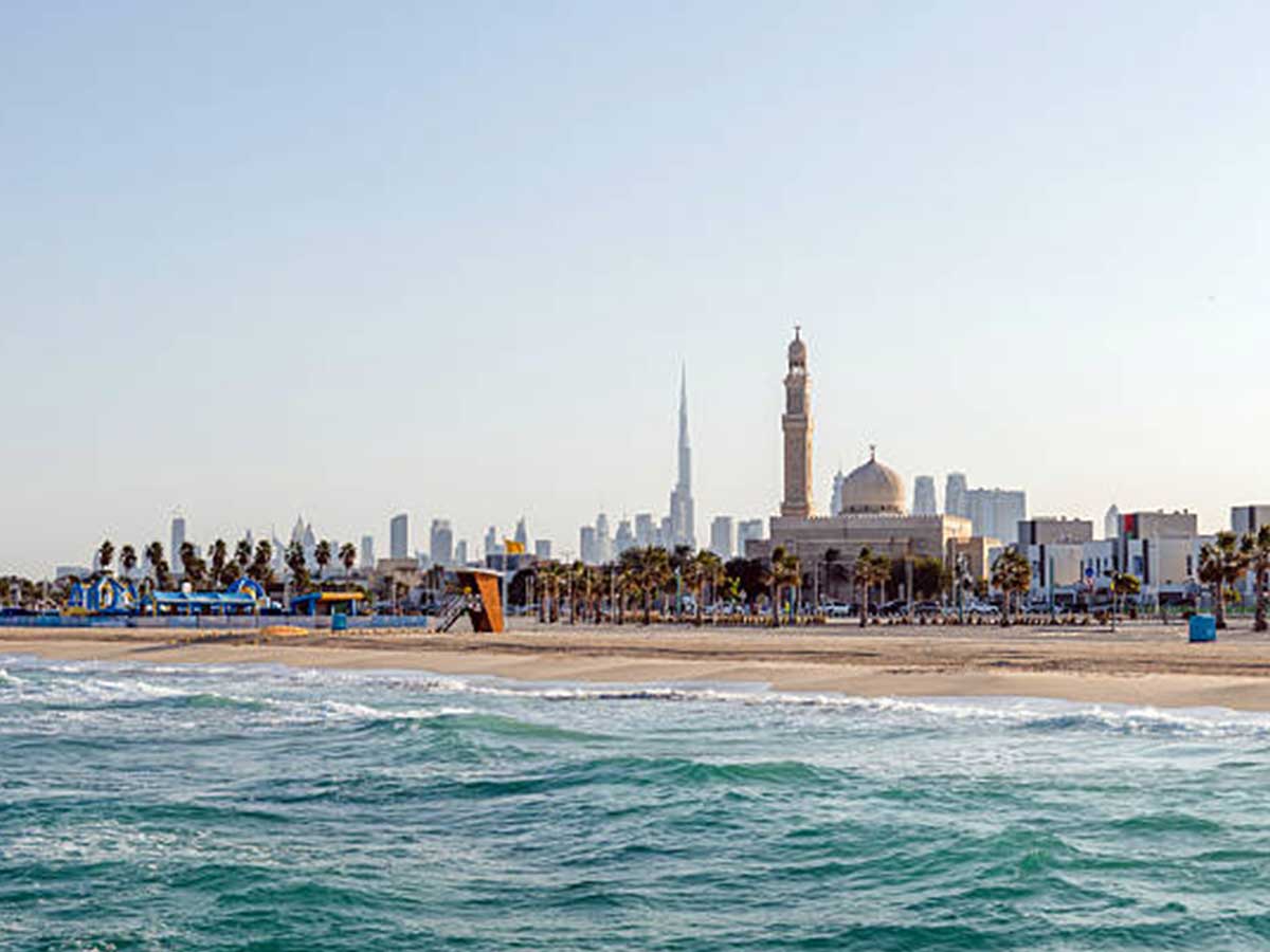  Water pools along a sandy beach, Dubai buildings in the background.