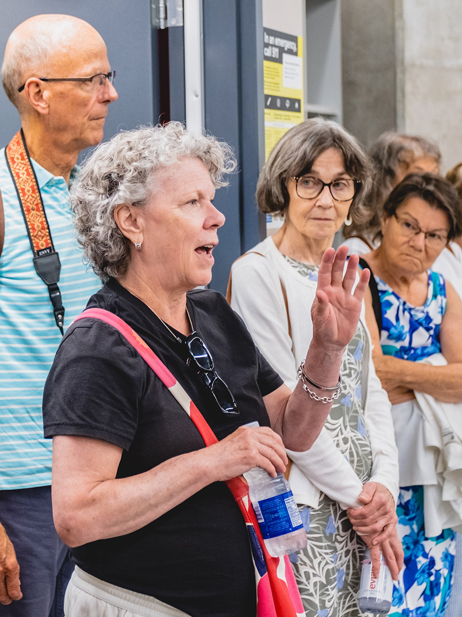 Woman has a hand up and speaks while others listen.
