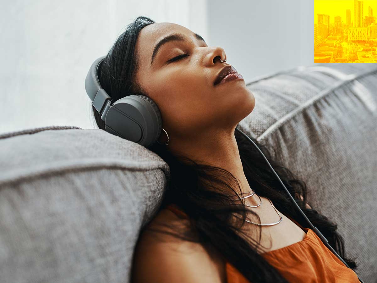 Person listening to music using headphones, sitting on a couch