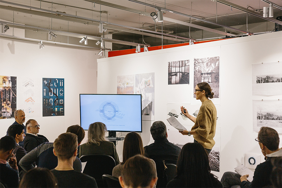 Masters student presenting her architectural work to a room full of people