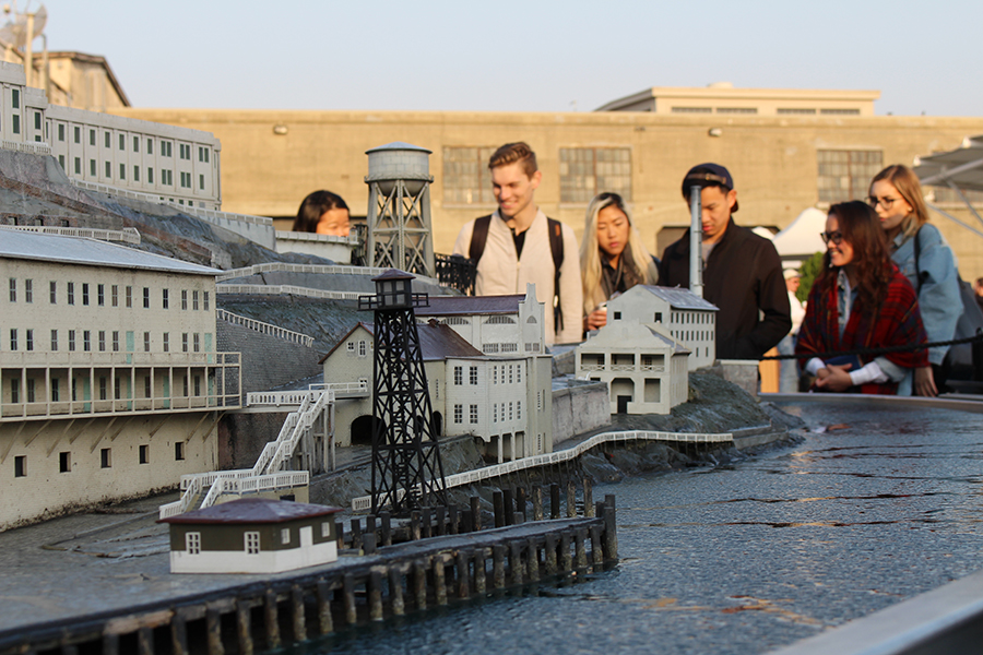 Students gather by a miniature model of a town