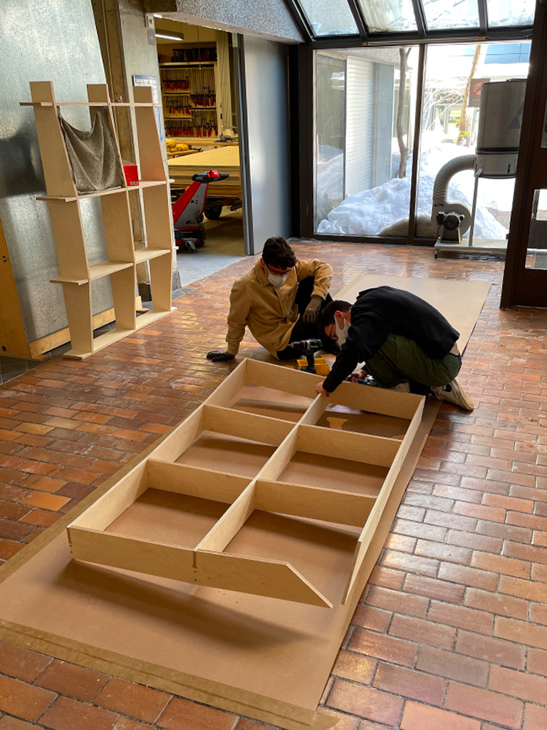 Students building a shelf-like structure with wood as part of the assembly of S'Winter.