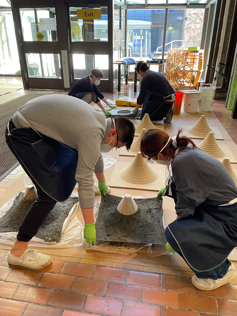 Students placing square blocks on top of a cone-like module as part of the assembly for S'Winter.