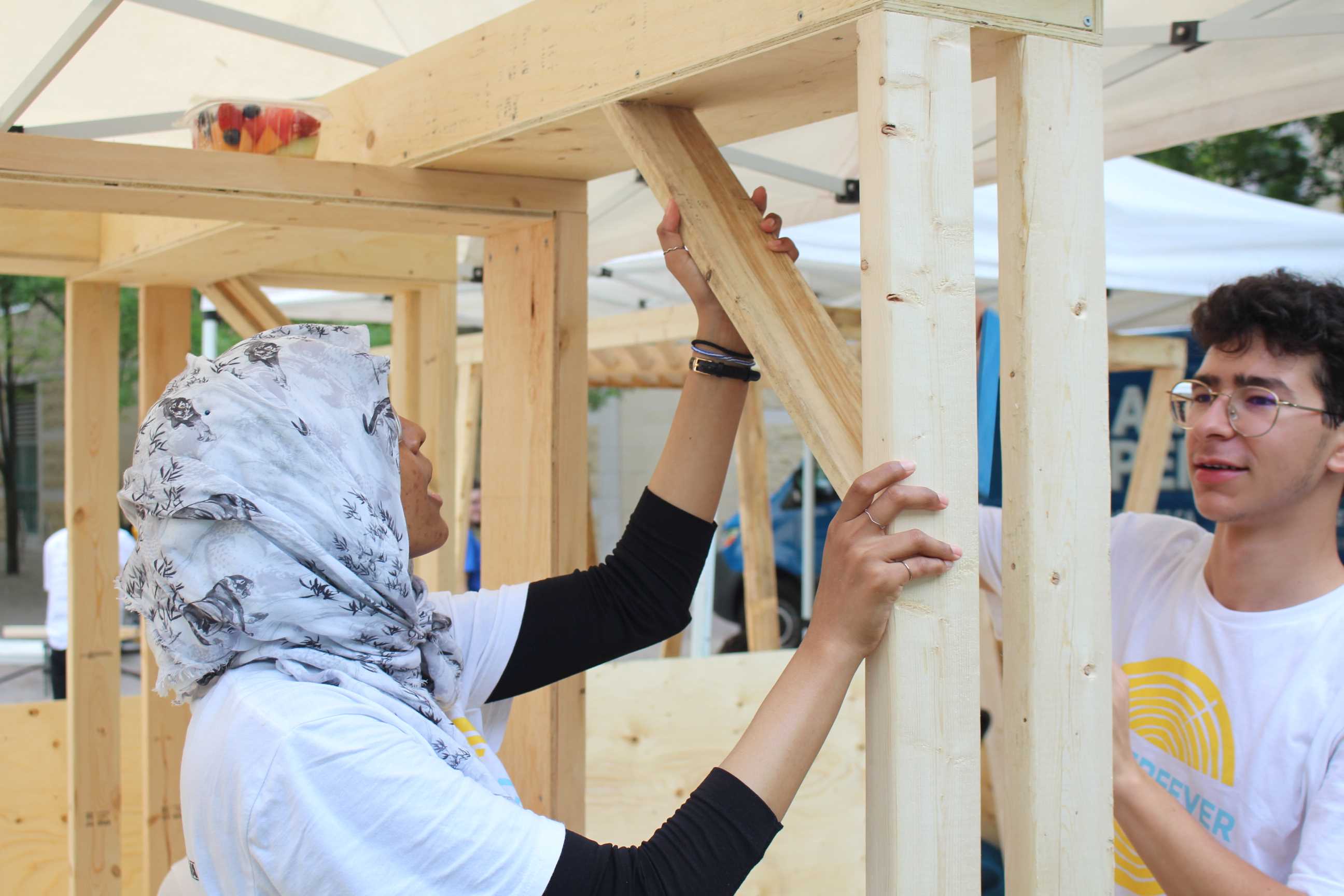 Students adding planks of wood to the roof of their Community Garden Pavilion. 