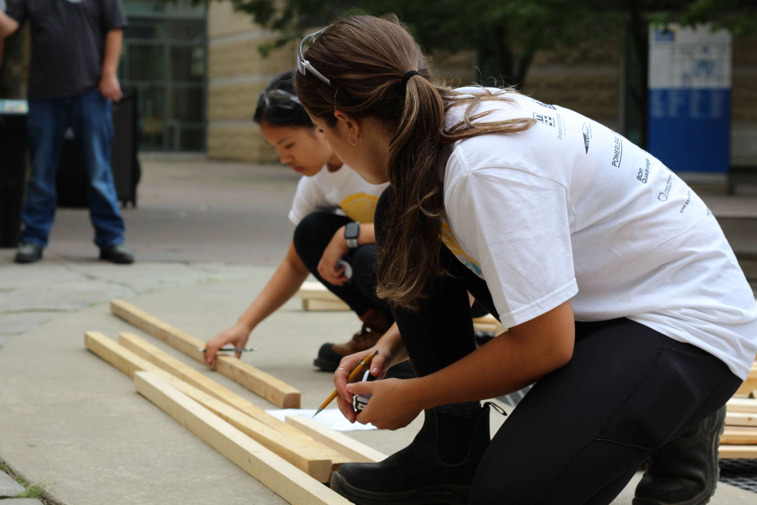 Students measuring planks of wood. 