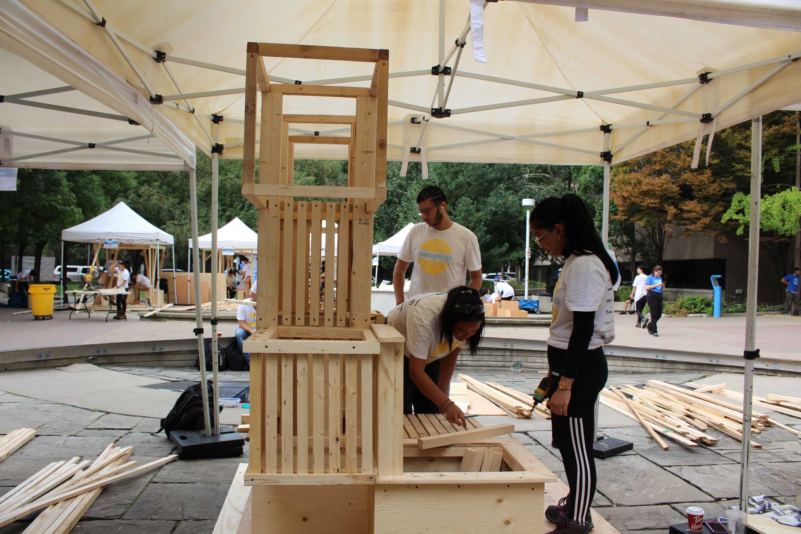 Students assembling their Community Garden Pavilion, which features stacks of wooden crate-like boxes. 