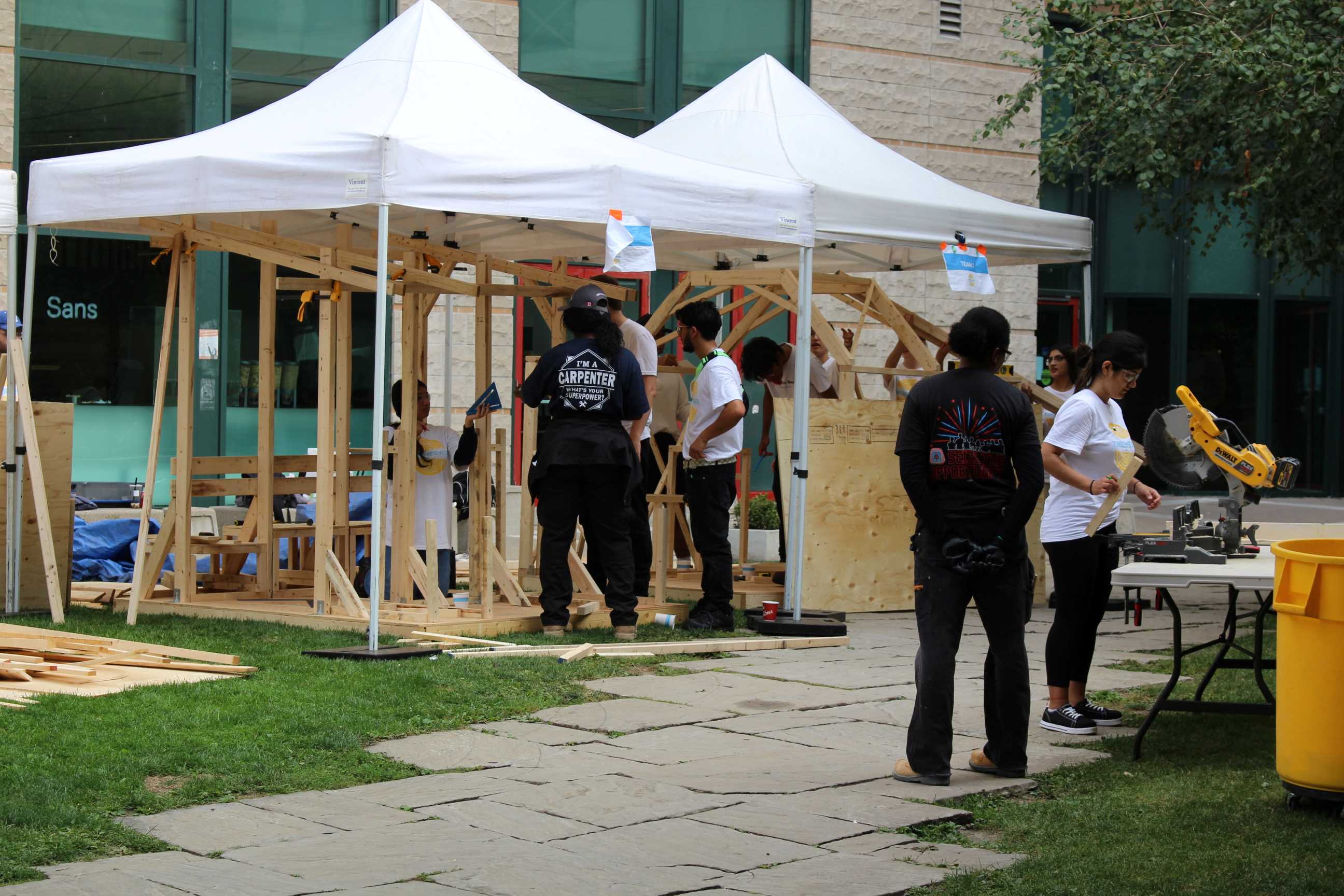 A wide-shot showcasing two tents with students assembling their Community Garden Pavilions. 
