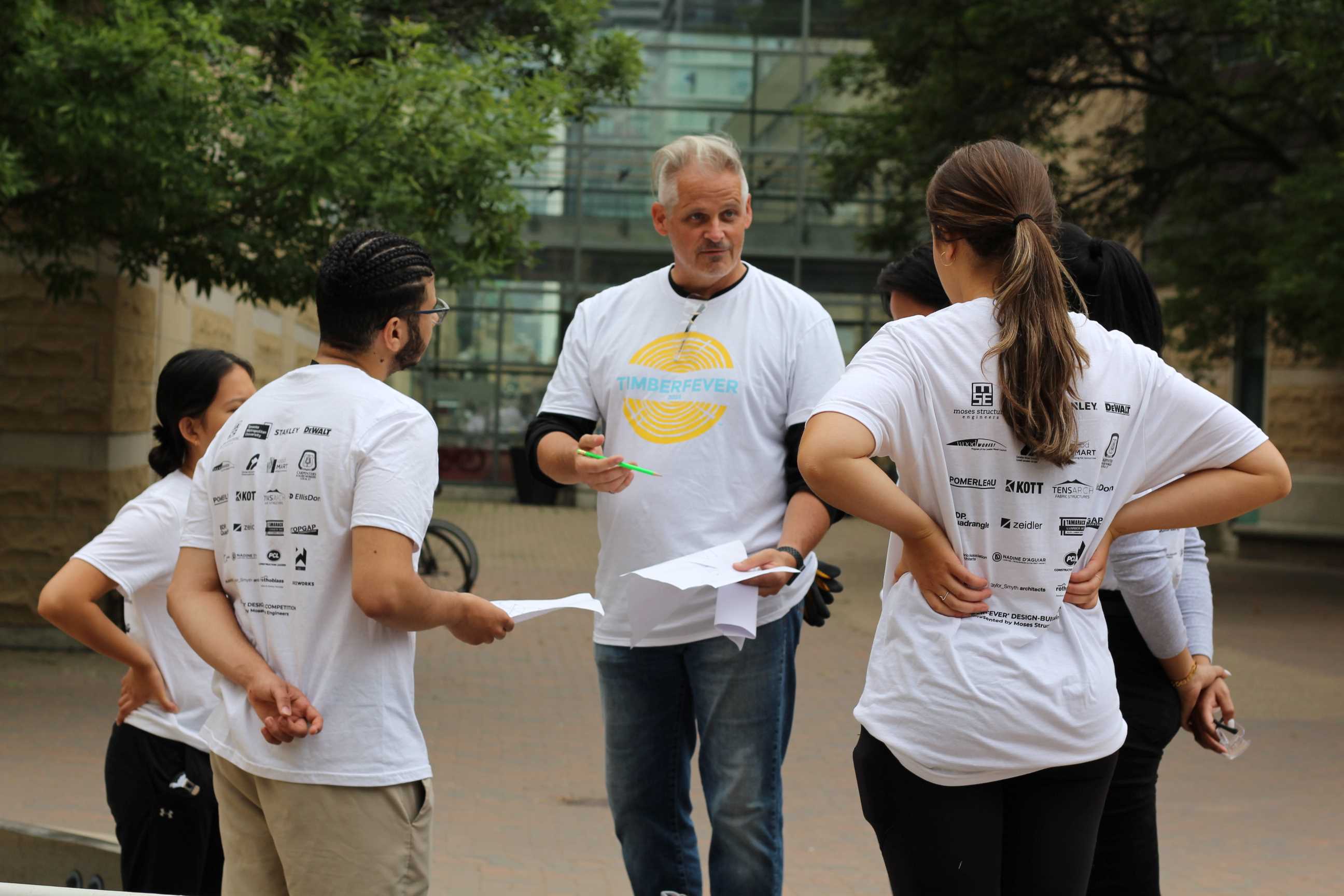 Students standing in a circle and discussing their drawings. 