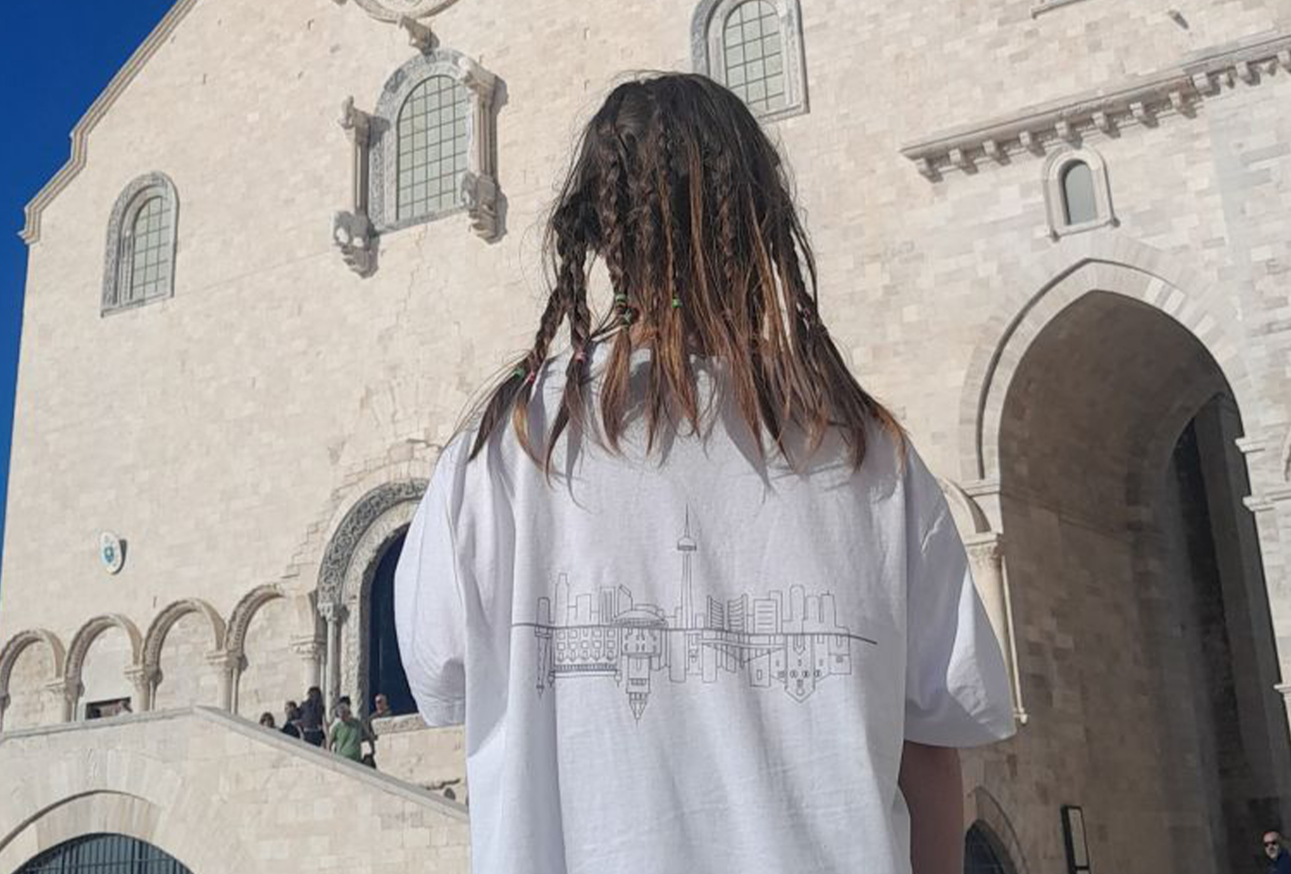 Student posing with a t-shirt designed by Narges Montevasseli, showing the Toronto and Bari cityscapes blended together