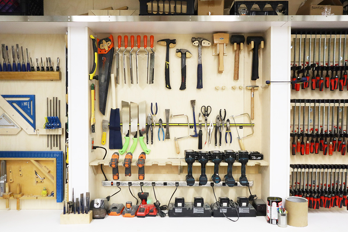 A shelving unit stores a variety of tools, including electric drills, hammers, hand saws and pliers. 
