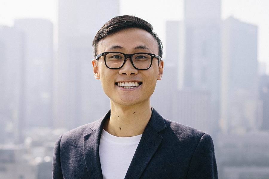 Henry Mai smiling with a city in the background