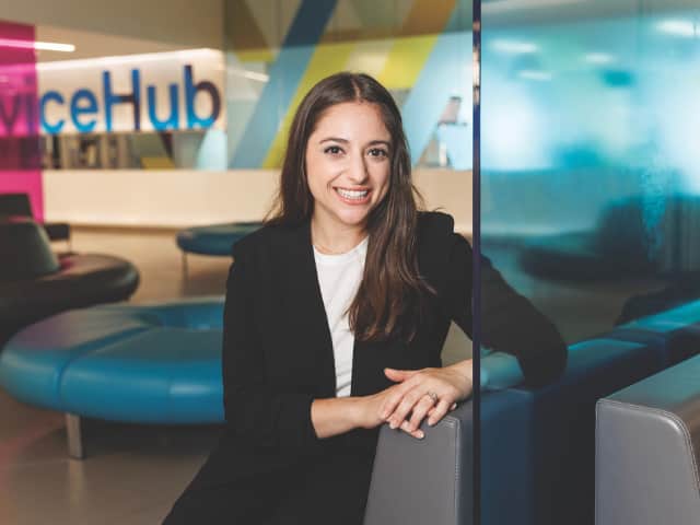 Woman seated in room with colourful furniture, smiling