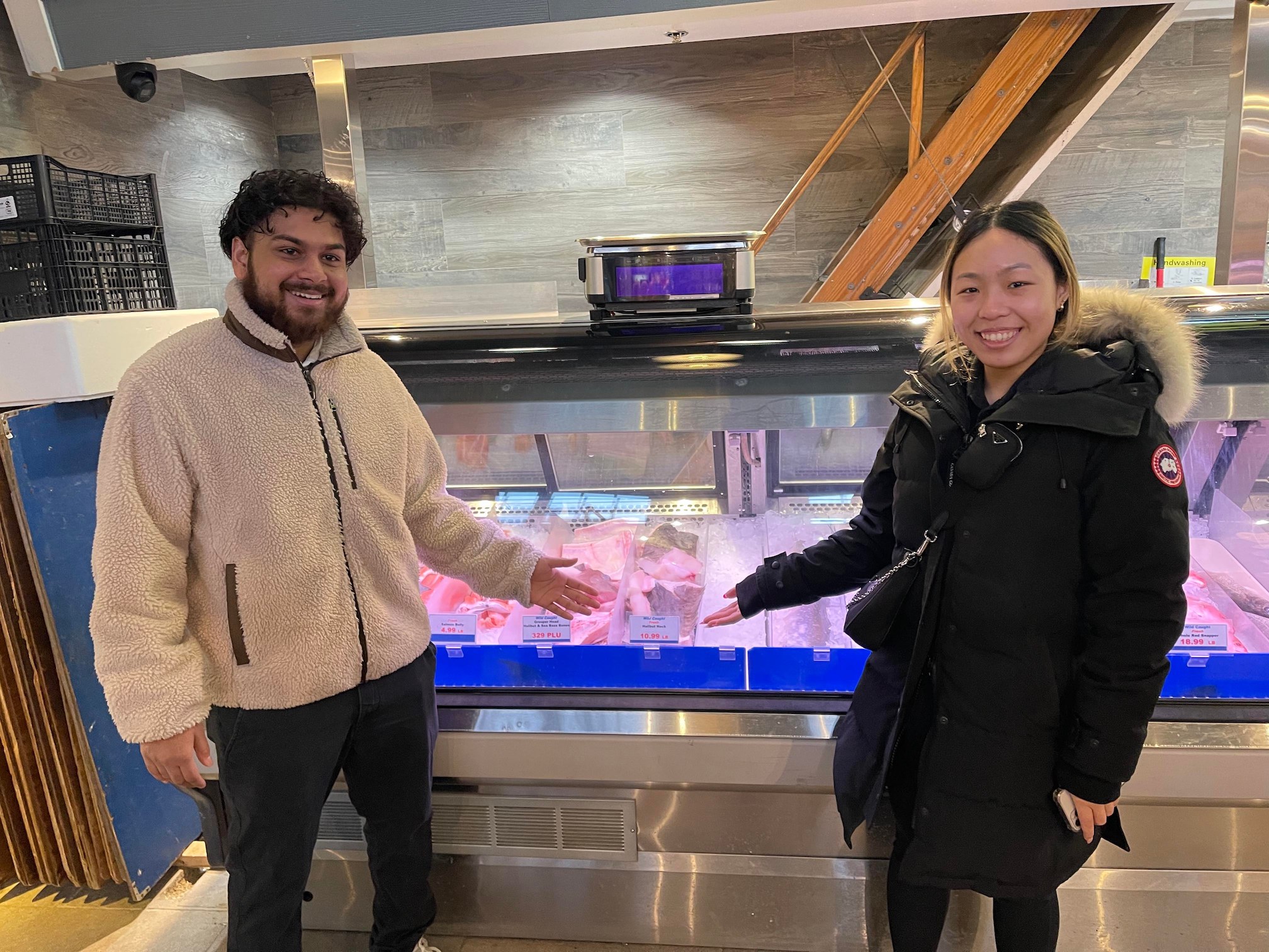 A pair of students pose in front of the butcher's display