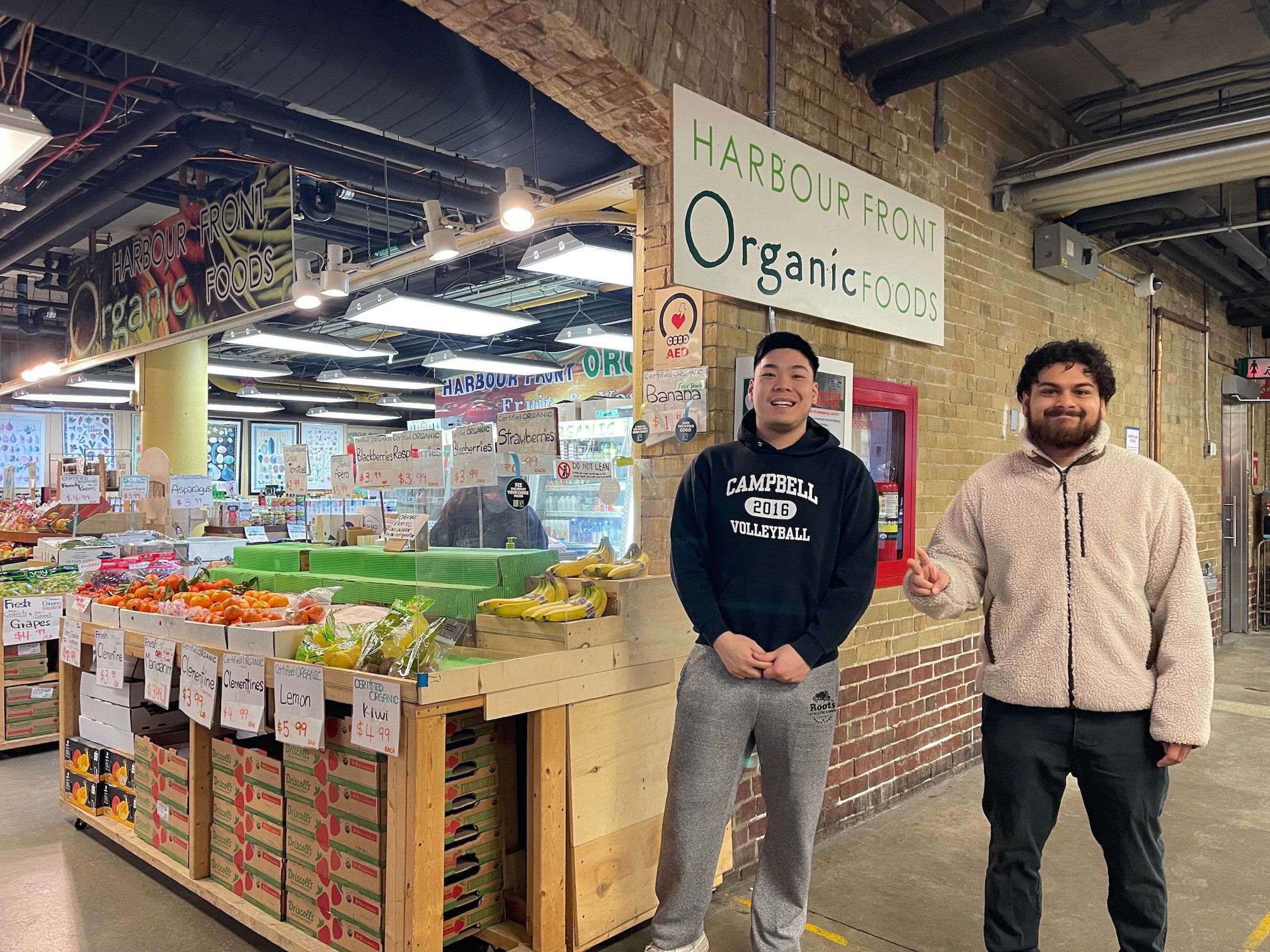 Two male students strike a pose in front of an organic food storefront