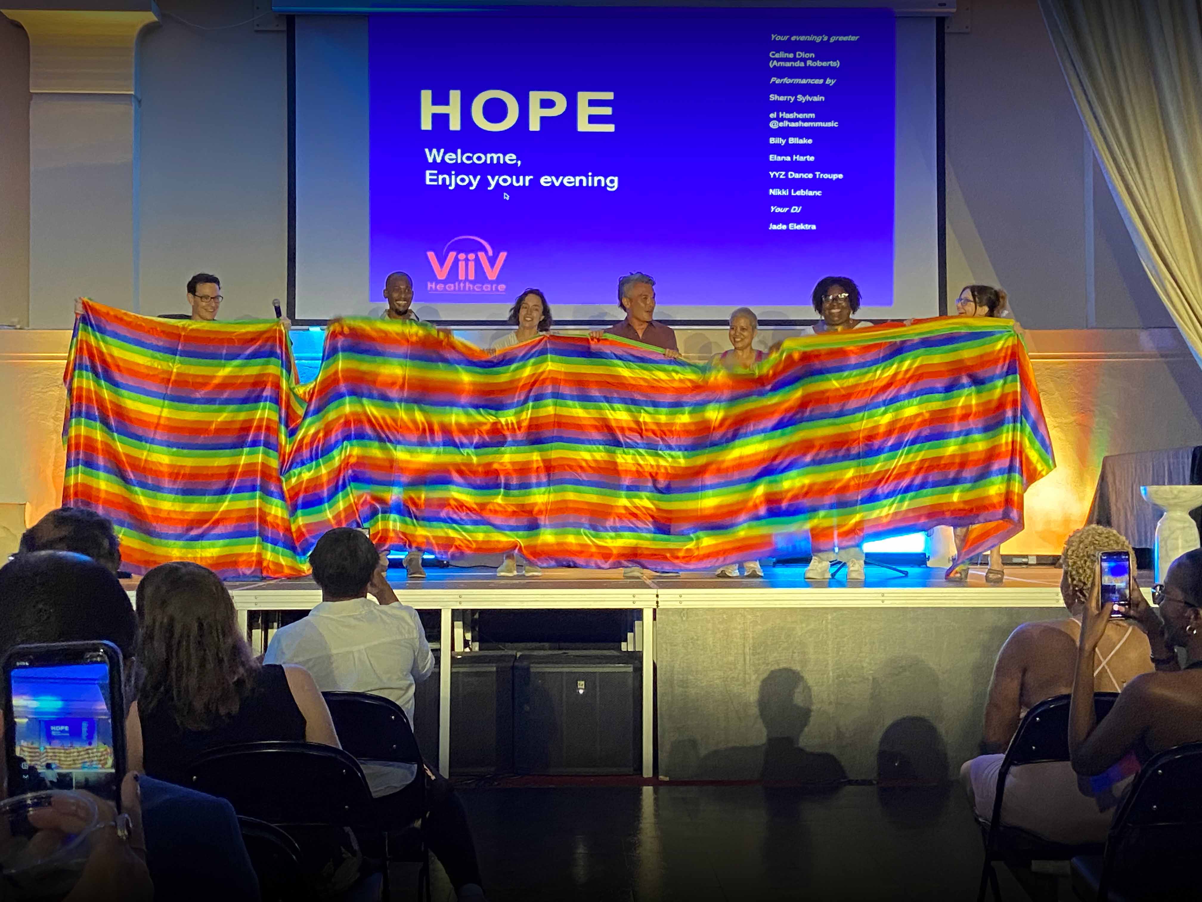 Student holding a pride flag on a stage.