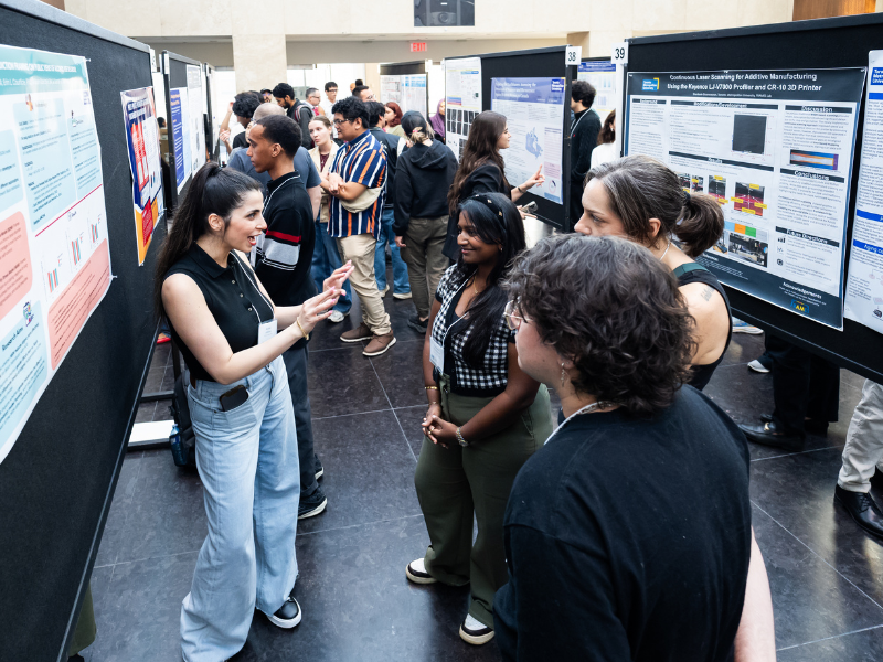 Mojdeh animatedly explains her work to interested attendees at a showcase.