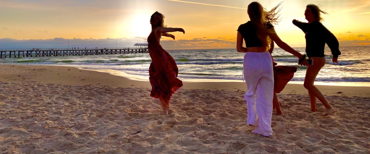 Community-Engaged Learning & Teaching PhotoVoice Exhibit - Four people dancing on the beach at the sunset