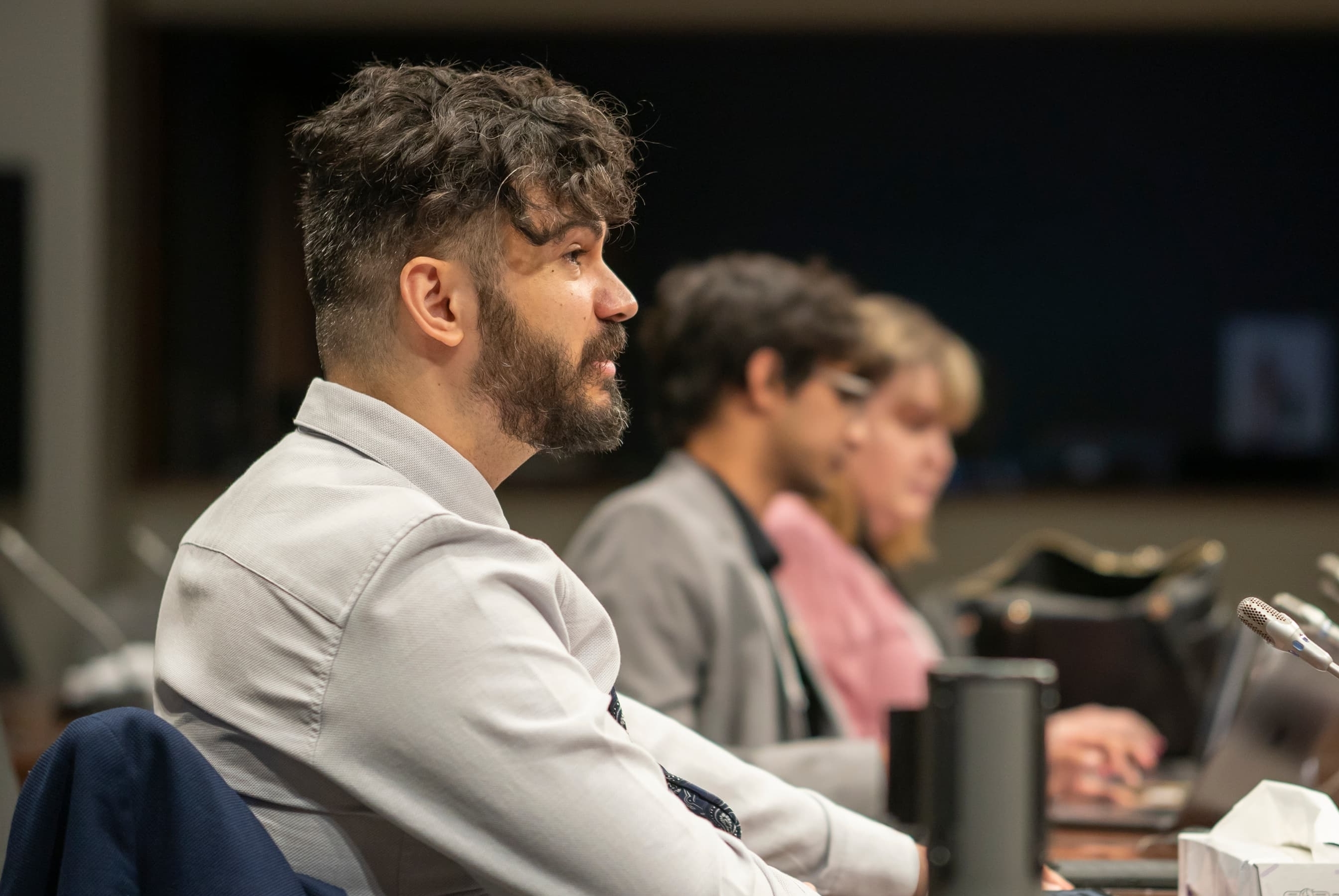 Group in conference room focus intently, surrounded by laptops and documents.