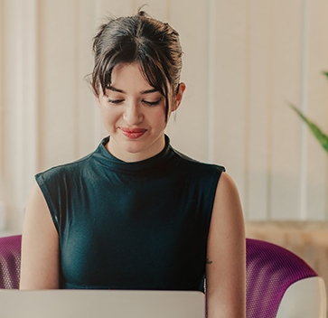 A female sitting on a chair with a laptop in the front