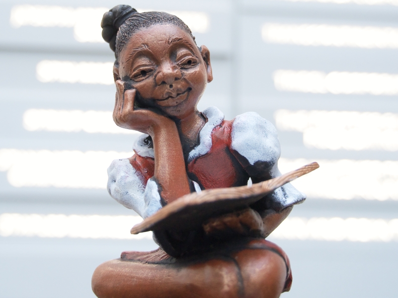 Statuette of a young Black girl with glasses reading a book