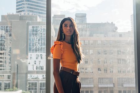 Student standing indoors with large windows behind her showing a city skyline