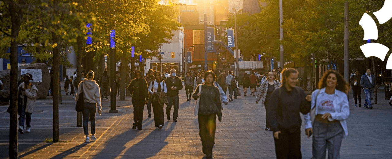 People walking in Toronto at sunset, TMU banners in the background