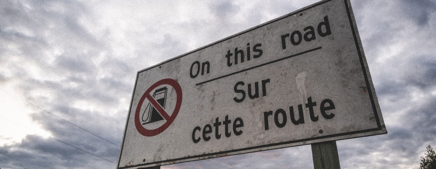 A road sign with the text "On this road / Sur cette route" in English and French and a symbol of no gas station available