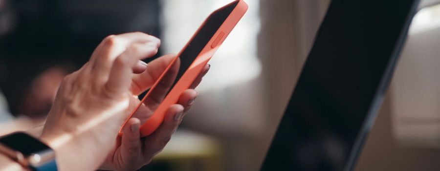 Someone holding a phone in front of a laptop screen