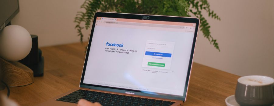 A laptop open on a table, the log-in page to Facebooko visible