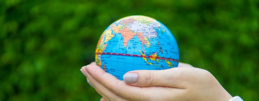 A pair of hands holding a miniature Earth