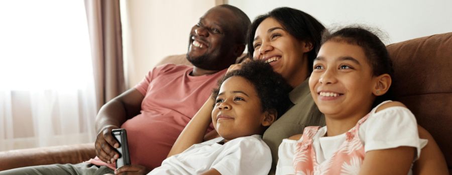 A Black family of four smiling on a couch