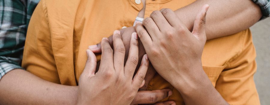 Close-up of two people embracing, highlighting a loving, intimate connection with intertwined hands.