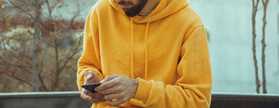 A young man, alone, texting on his smarthphone