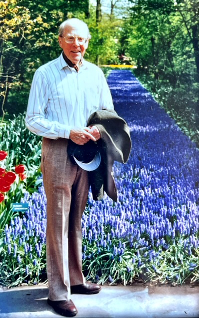 Geoffrey Bruce smiling in front of a patch of purple flowers