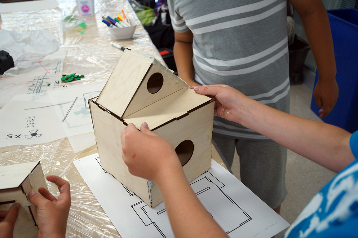 Camper building a miniture laser cut wooden house.