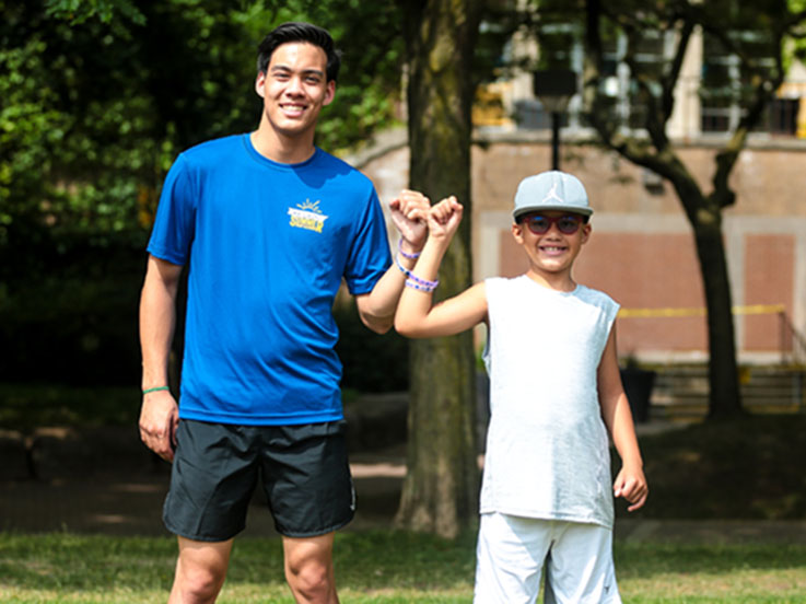 A camp staff and camper bump fists in solidarity