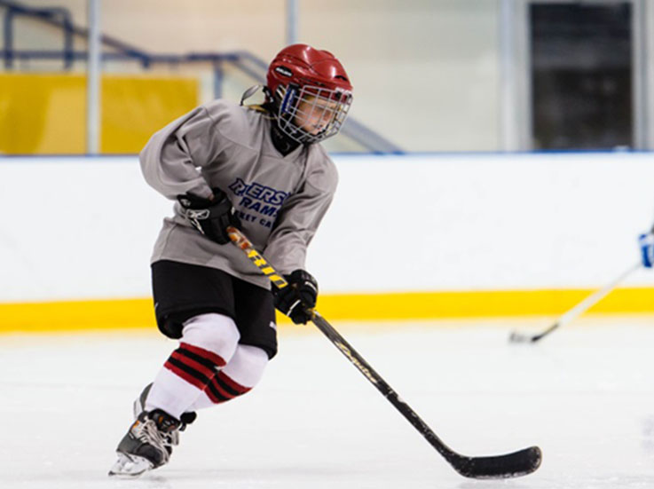 A hockey player skates with their stick held with two hands