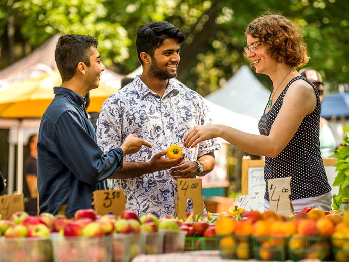 Students buying apples from farmer at farmer's market
