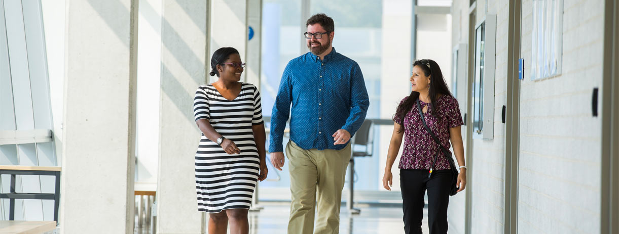 Three employees chatting while walking through a hallway in Ryerson's Engineering buildiing.