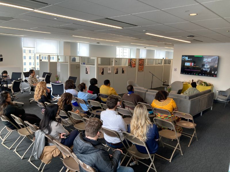 A group of people sitting in the Centre watching something on the television