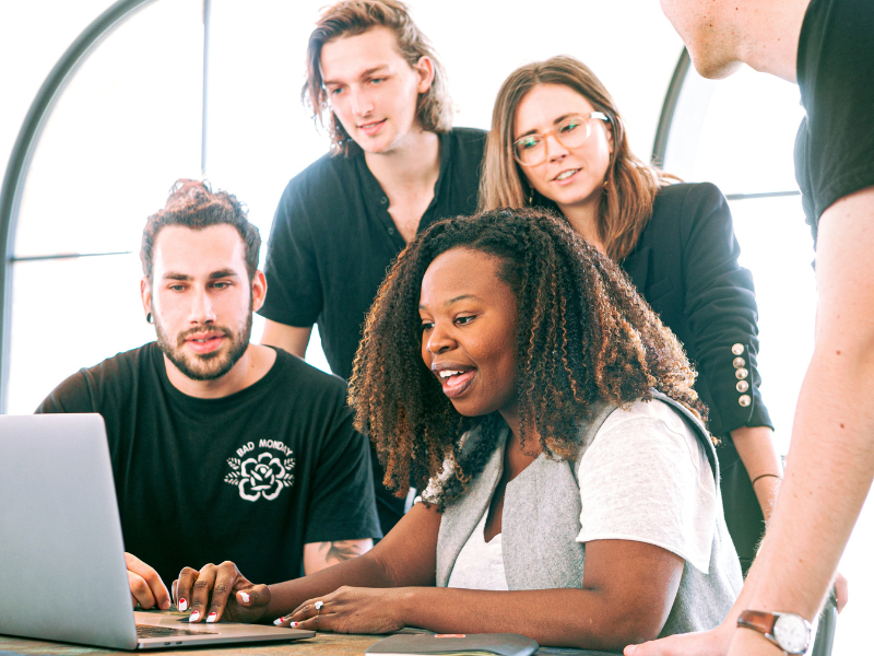 Group of 5 people sitting around a laptop