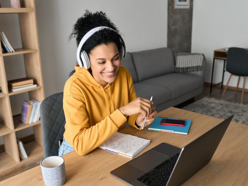 A person wearing headphones sitting at a desk in front of a laptop