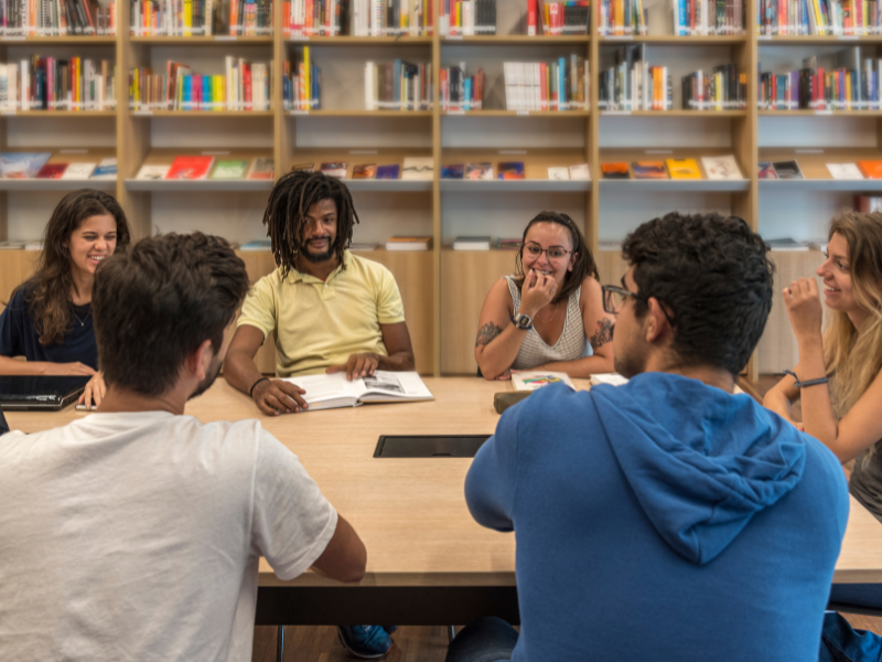 A group of people having a discussion while sitting around a table.